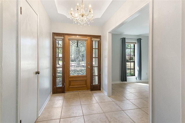 entryway featuring light tile patterned flooring, a notable chandelier, baseboards, and a tray ceiling