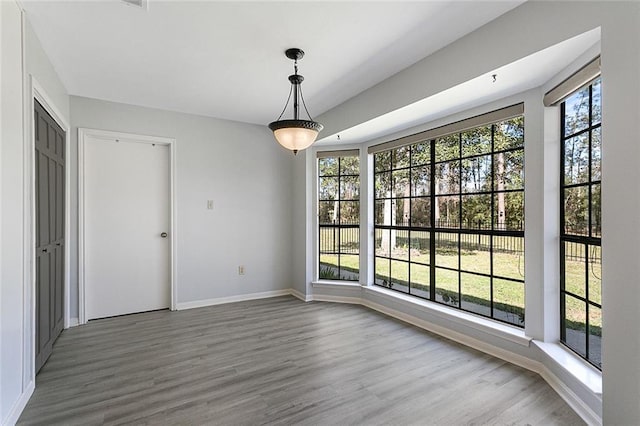 unfurnished dining area with a healthy amount of sunlight, baseboards, and wood finished floors