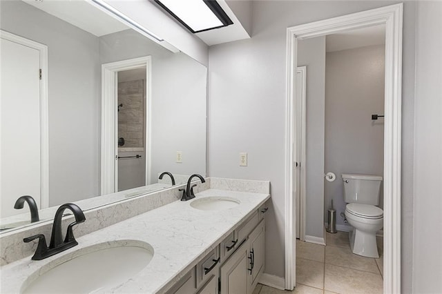 bathroom featuring tile patterned floors, double vanity, toilet, and a sink