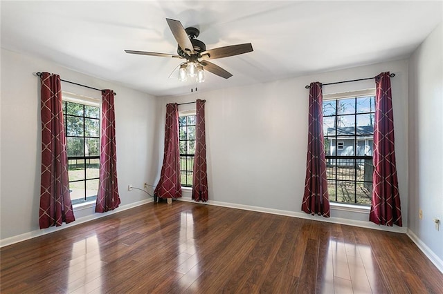 empty room featuring a ceiling fan, plenty of natural light, wood finished floors, and baseboards