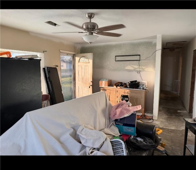 bedroom with freestanding refrigerator, a ceiling fan, and concrete flooring