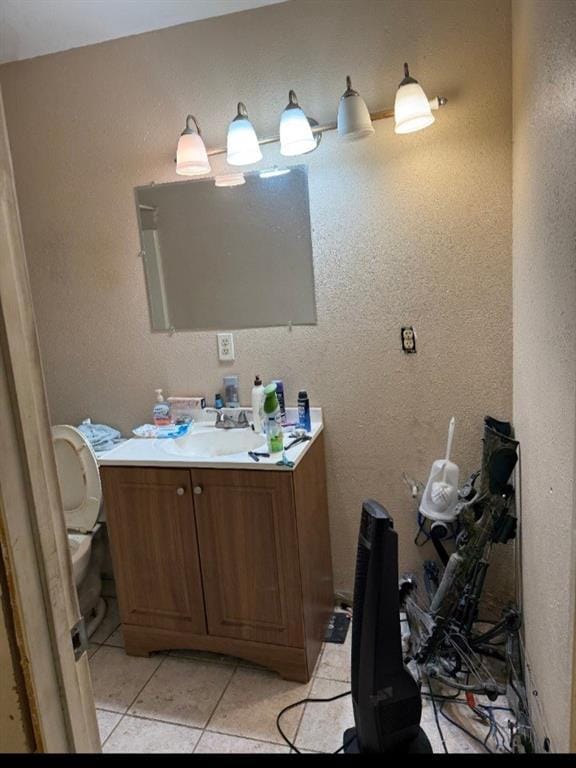 bathroom with toilet, vanity, and tile patterned flooring