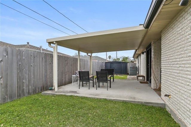 view of patio / terrace with a storage shed, fence, and an outbuilding