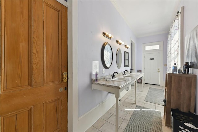 bathroom with tile patterned floors, crown molding, baseboards, and a sink