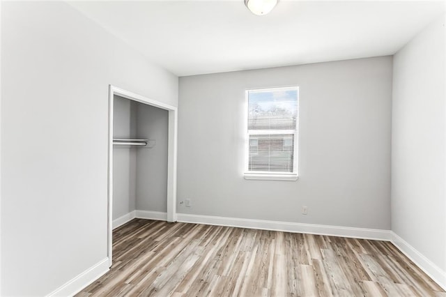 unfurnished bedroom featuring a closet, baseboards, and wood finished floors