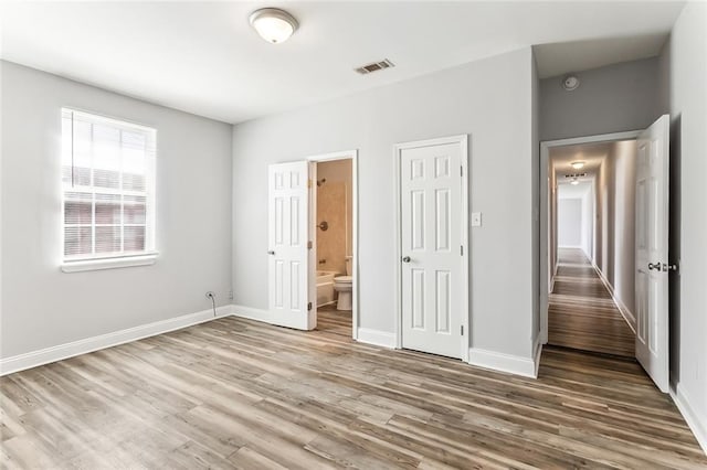 unfurnished bedroom featuring visible vents, baseboards, and wood finished floors