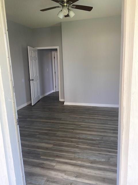 spare room featuring dark wood finished floors, baseboards, and ceiling fan