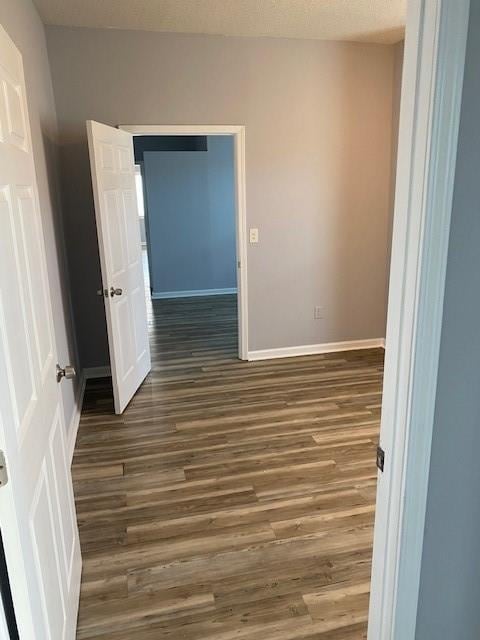 unfurnished room with dark wood-style floors and baseboards