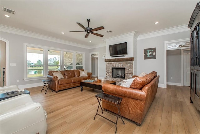 living room featuring light wood-type flooring, visible vents, ornamental molding, a ceiling fan, and a fireplace