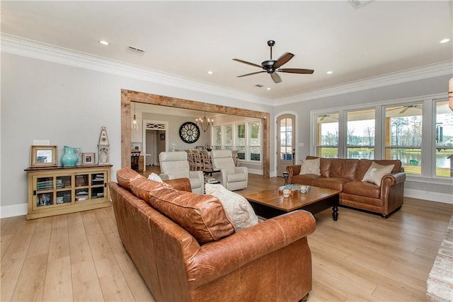 living room featuring ornamental molding, ceiling fan with notable chandelier, visible vents, and light wood-type flooring