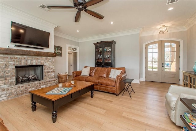 living area with visible vents, ornamental molding, french doors, light wood finished floors, and ceiling fan