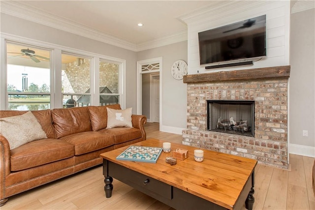 living room with ornamental molding, hardwood / wood-style floors, baseboards, a brick fireplace, and ceiling fan