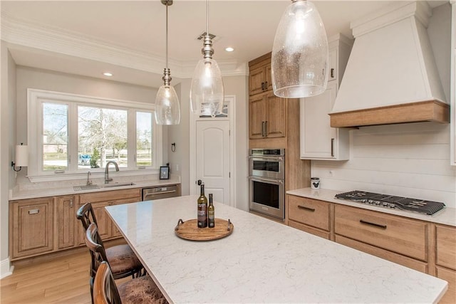 kitchen featuring light stone countertops, custom range hood, light wood-style flooring, appliances with stainless steel finishes, and a sink