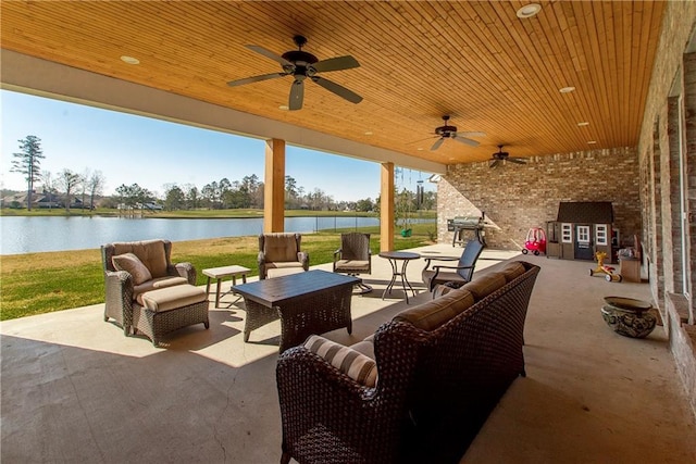 view of patio / terrace with an outdoor living space, a water view, area for grilling, and a ceiling fan