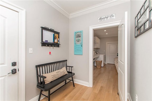 hallway with baseboards, washing machine and dryer, crown molding, and light wood finished floors