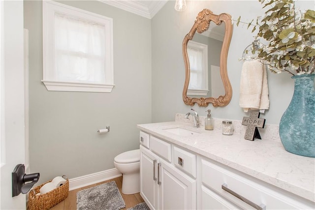 bathroom with baseboards, toilet, ornamental molding, wood finished floors, and vanity