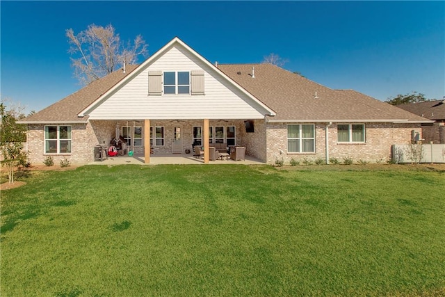 rear view of house featuring brick siding, a lawn, and a patio