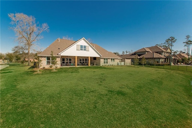 rear view of house with a lawn and fence