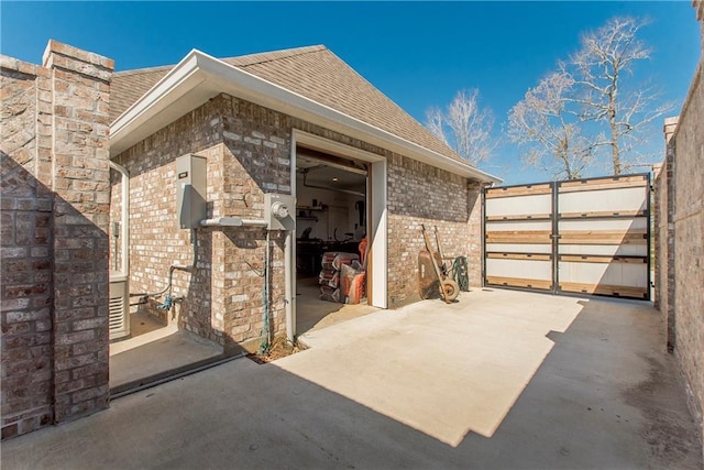 view of side of home with brick siding and roof with shingles