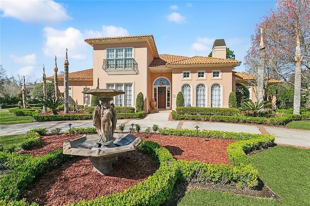 mediterranean / spanish house with stucco siding, a chimney, and a tiled roof