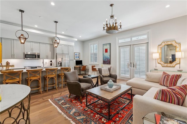 living area featuring a notable chandelier, recessed lighting, and light wood-style floors