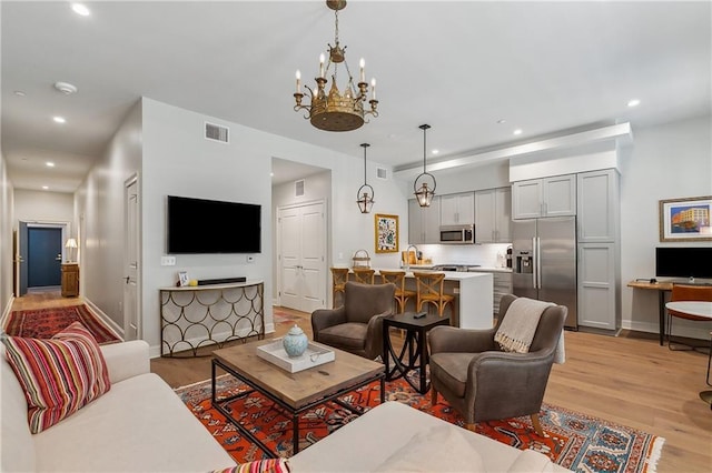 living area with visible vents, recessed lighting, light wood-style floors, an inviting chandelier, and baseboards