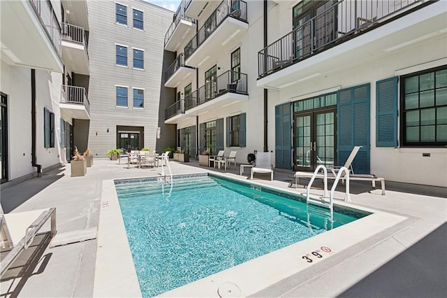 community pool with french doors and a patio