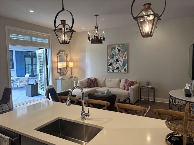 interior space with pendant lighting, open floor plan, light countertops, a sink, and a notable chandelier