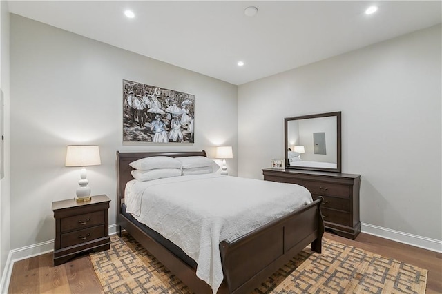 bedroom featuring recessed lighting, baseboards, electric panel, and wood finished floors