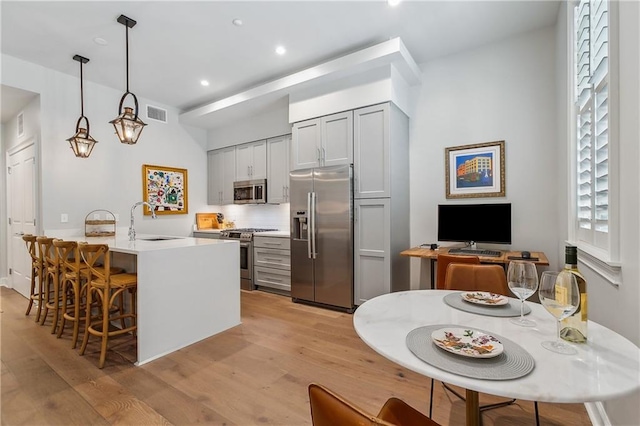 kitchen with a sink, a peninsula, light wood-style floors, and stainless steel appliances