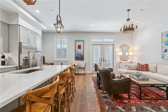 living room with recessed lighting, baseboards, an inviting chandelier, and light wood-style flooring