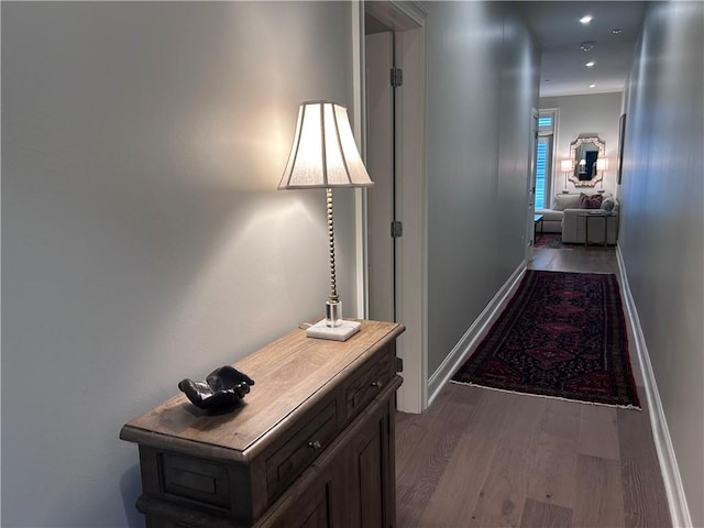 corridor with baseboards and wood finished floors