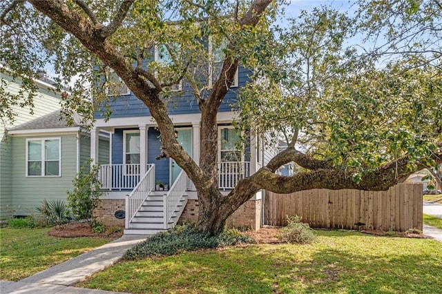 view of front of home with a porch, fence, a front yard, crawl space, and stairs