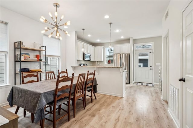 dining area featuring a chandelier, visible vents, plenty of natural light, and light wood-style floors