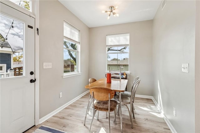 dining space with visible vents, light wood-style floors, baseboards, and a chandelier