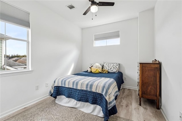 bedroom featuring visible vents, multiple windows, baseboards, and wood finished floors