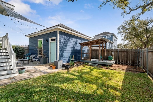 back of property featuring a deck, a fenced backyard, a yard, an outdoor structure, and a patio area