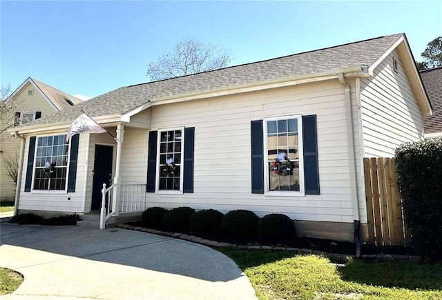 view of front of house featuring roof with shingles and fence