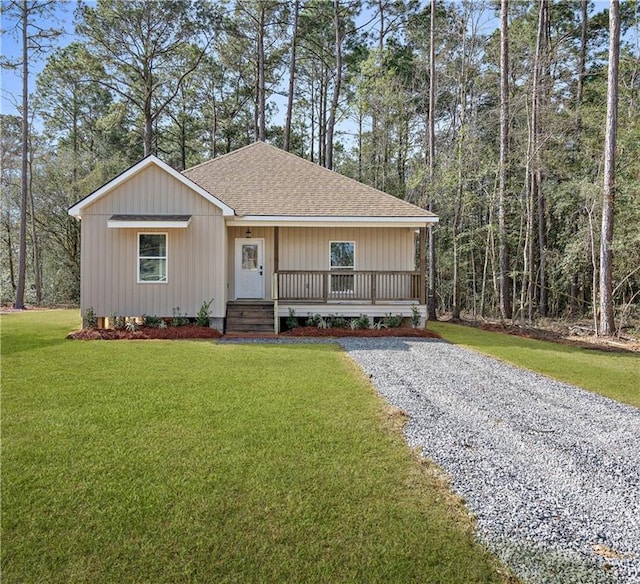 view of front of house featuring a porch, driveway, a front lawn, and roof with shingles