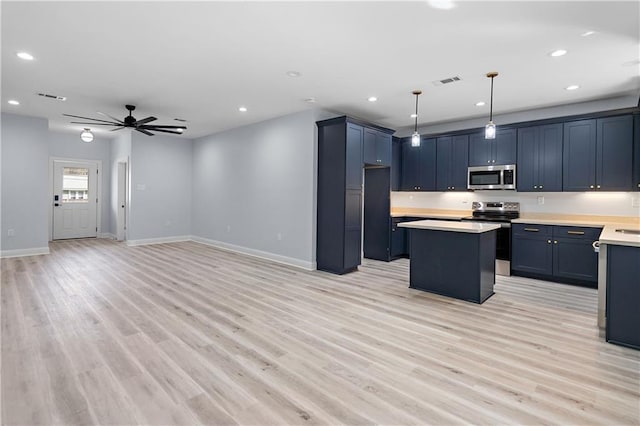 kitchen featuring visible vents, a kitchen island, light countertops, light wood-type flooring, and appliances with stainless steel finishes