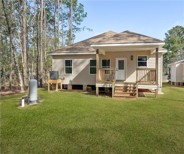 rear view of house with central air condition unit, a lawn, and a shingled roof