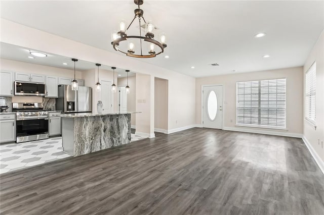 kitchen with wood finished floors, an inviting chandelier, recessed lighting, appliances with stainless steel finishes, and tasteful backsplash