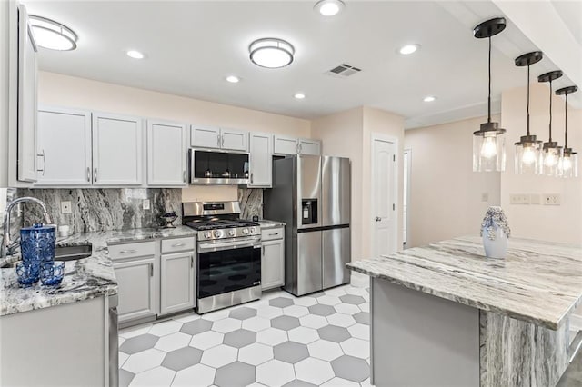 kitchen featuring visible vents, light stone countertops, decorative backsplash, appliances with stainless steel finishes, and a sink