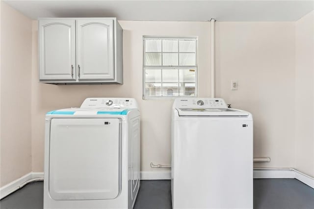 clothes washing area with cabinet space, baseboards, and washer and clothes dryer