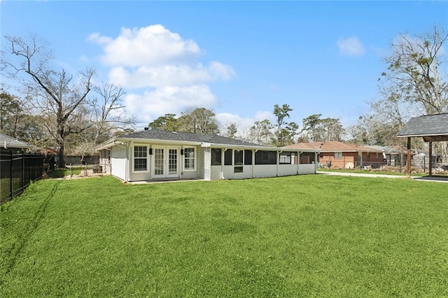 rear view of property featuring fence, french doors, and a lawn