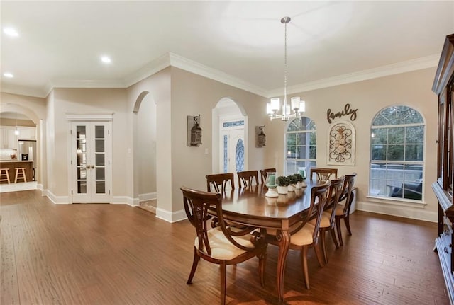 dining space with arched walkways, dark wood-style floors, and an inviting chandelier