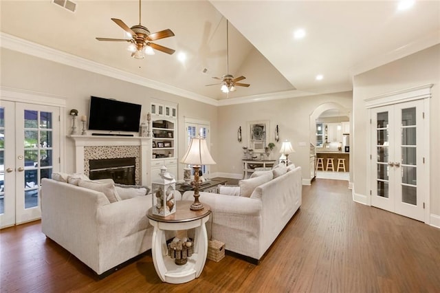 living room featuring dark wood finished floors, french doors, arched walkways, and ceiling fan