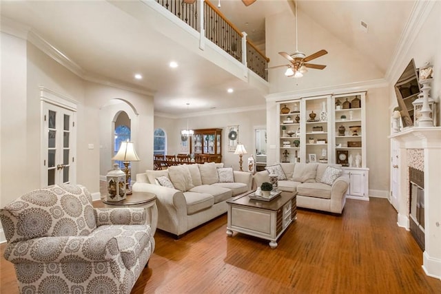 living room with ceiling fan, arched walkways, wood finished floors, and crown molding