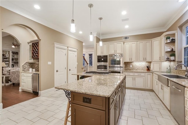 kitchen with a breakfast bar area, visible vents, arched walkways, ceiling fan, and stainless steel appliances