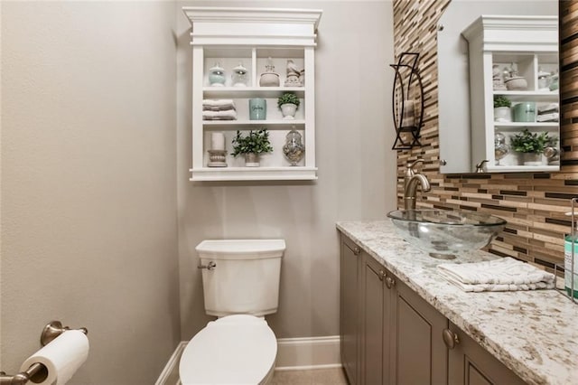 half bathroom with vanity, toilet, baseboards, and tasteful backsplash